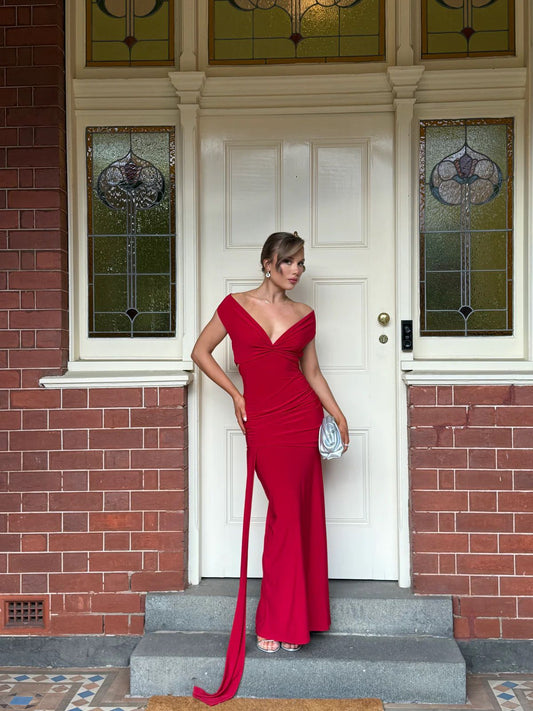 Woman in a red evening gown standing on steps in front of a house with stained glass windows.
