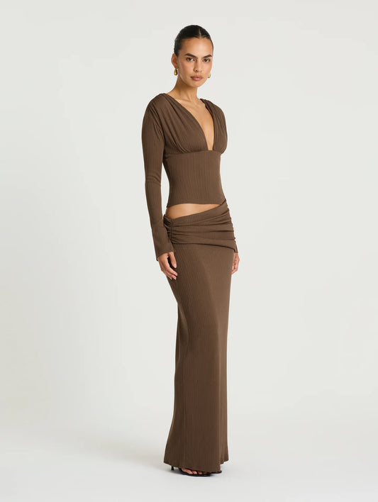 Woman wearing a brown long-sleeve gown on a white background
