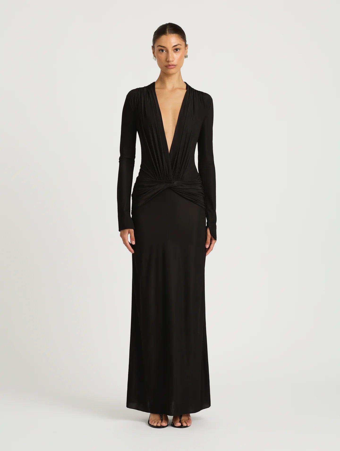 A model wearing a long-sleeved black maxi dress with a plunging V-neckline.