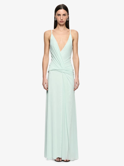 A model wearing a floor-length mint green gown with spaghetti straps, a deep V-neckline, and a draped wrap-style bodice against a plain light gray background.