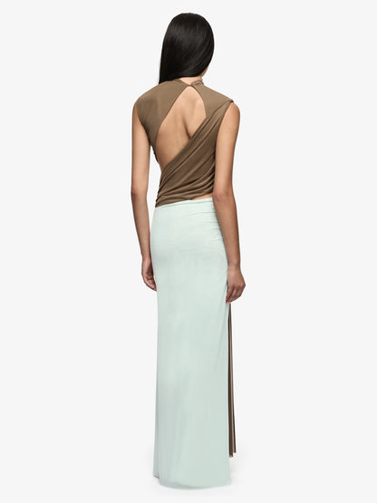 A model shown from the back wearing a sleeveless maxi dress with a draped brown back and a long mint green skirt with side slits, against a plain light gray background.