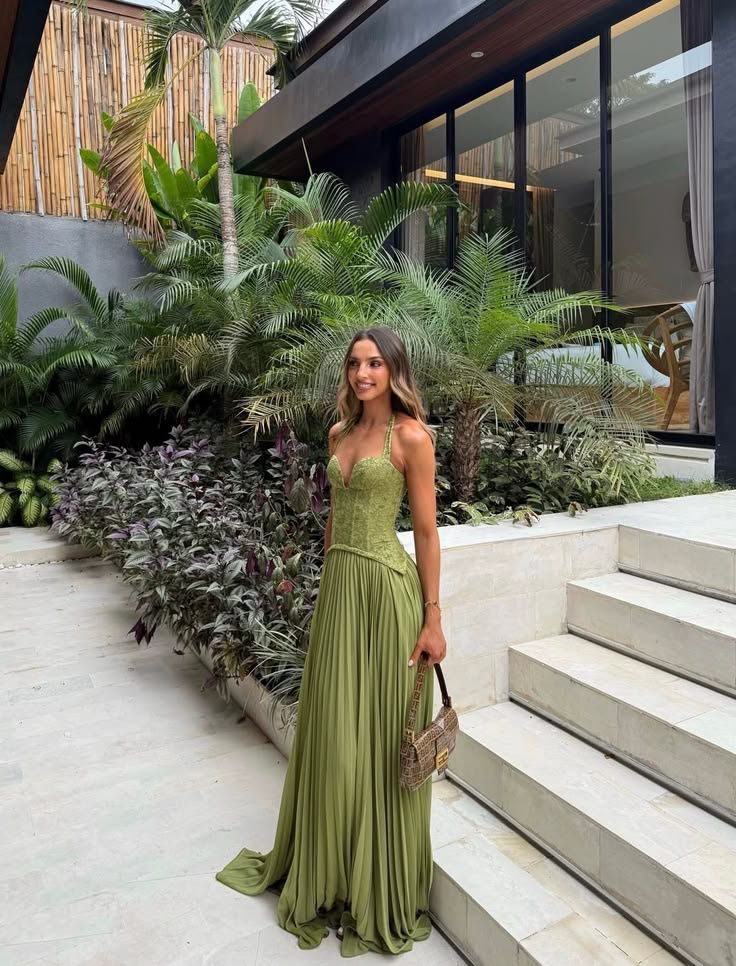 Woman in a green dress standing in front of a modern building with tropical plants.