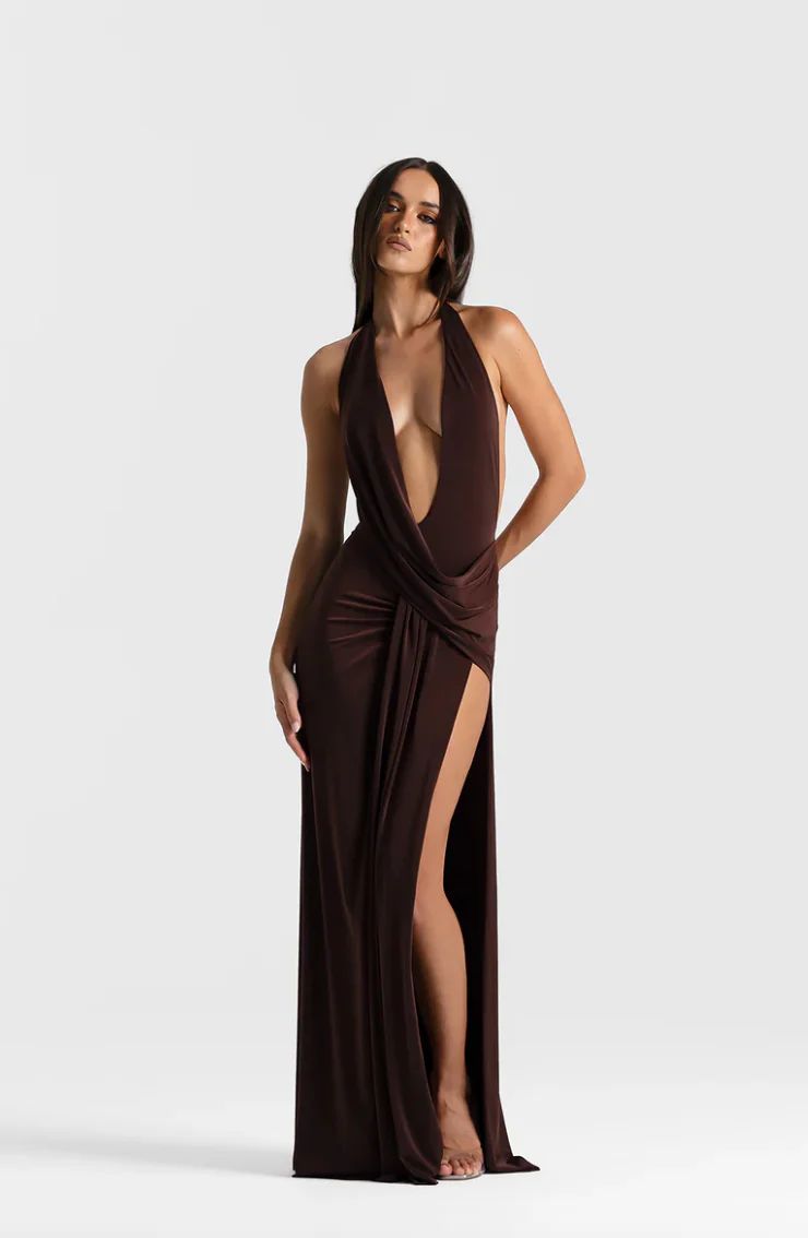 Woman wearing a brown evening gown with a deep neckline and slit on a white background