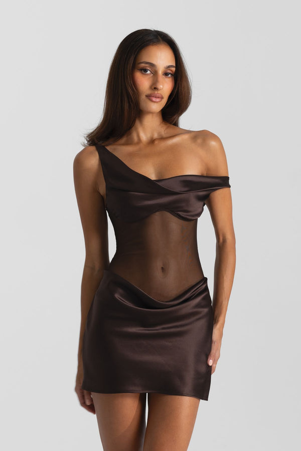 A woman modeling a dark brown satin off-the-shoulder mini dress with sheer mesh panels on a light gray studio background.